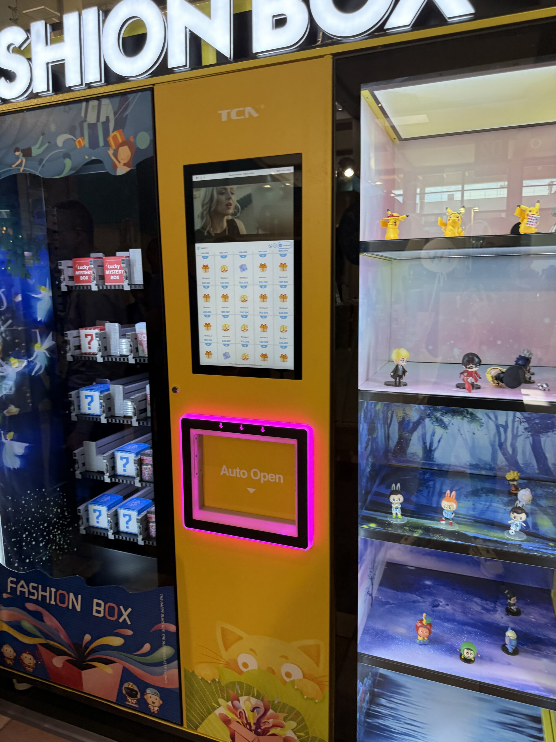 Lit display case cabinet holding collectible figures beside a trading card vending machine